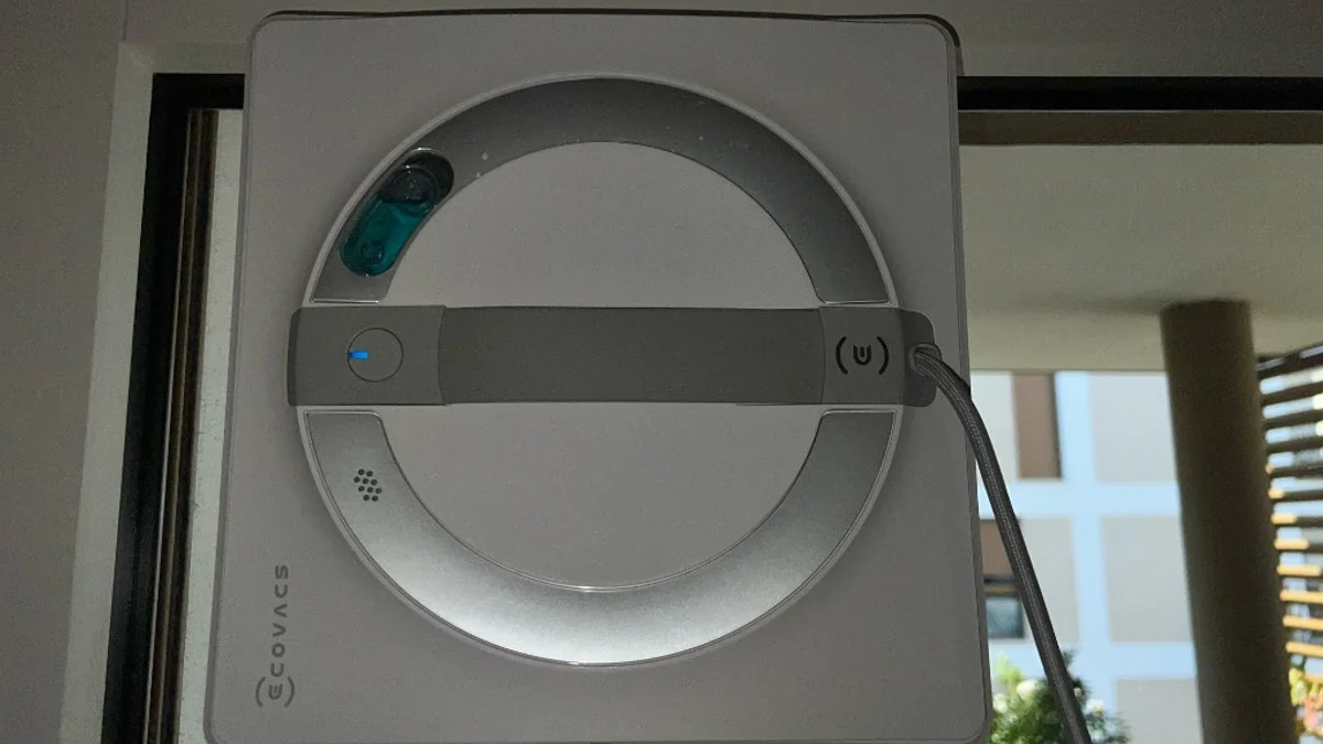 Ecovacs Winbot W2 Pro en action sur une baie vitrée, réservoir de liquide Lavaspi visible